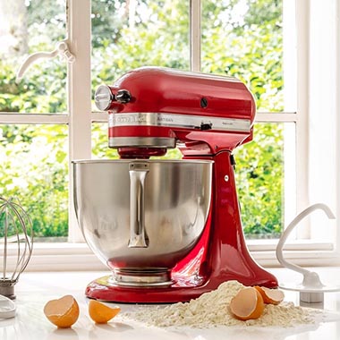 Een rode KitchenAid keukenmachine, eieren en bloem in een keuken